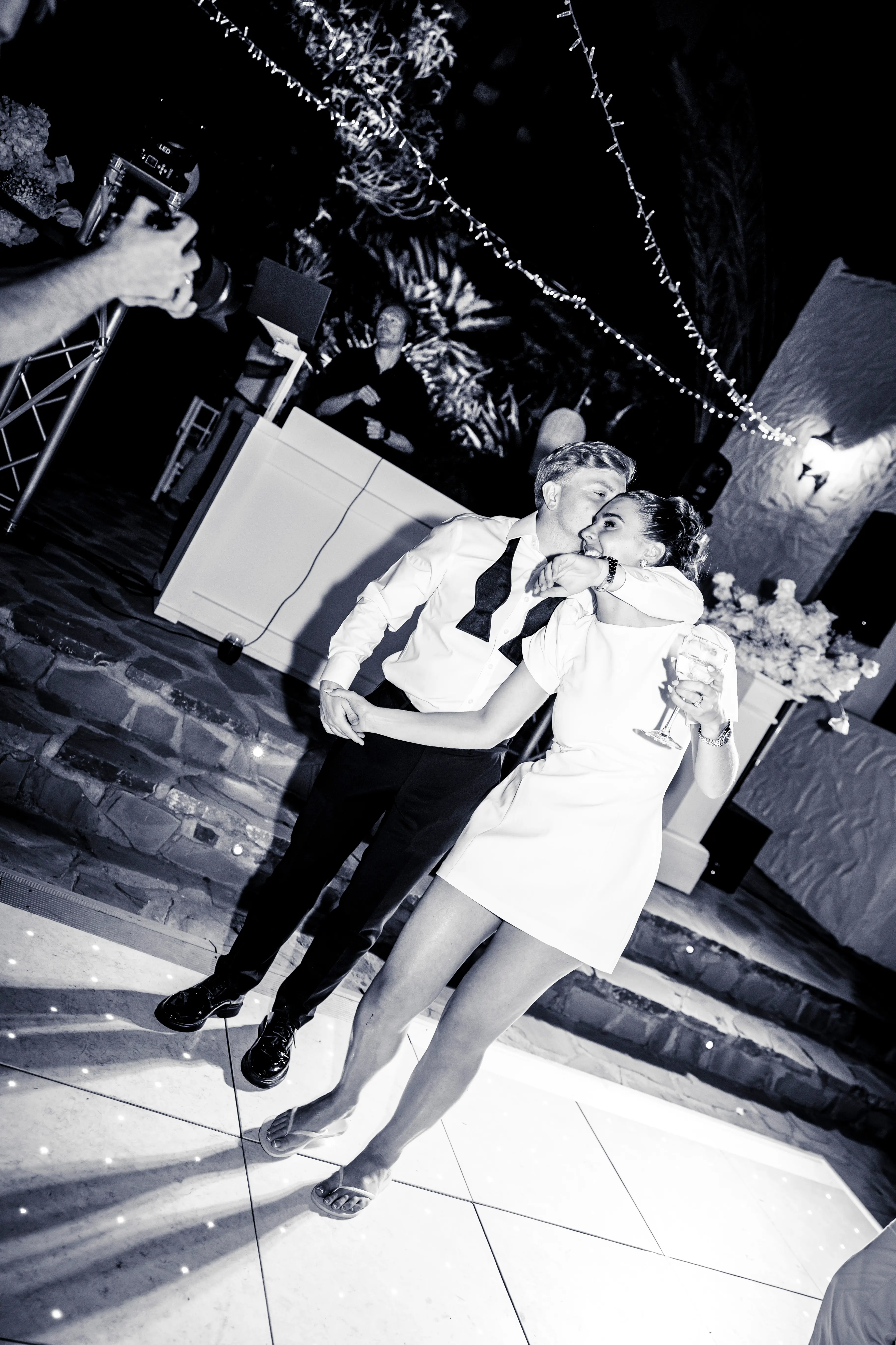 A couple dancing under fairy lights, in black and white