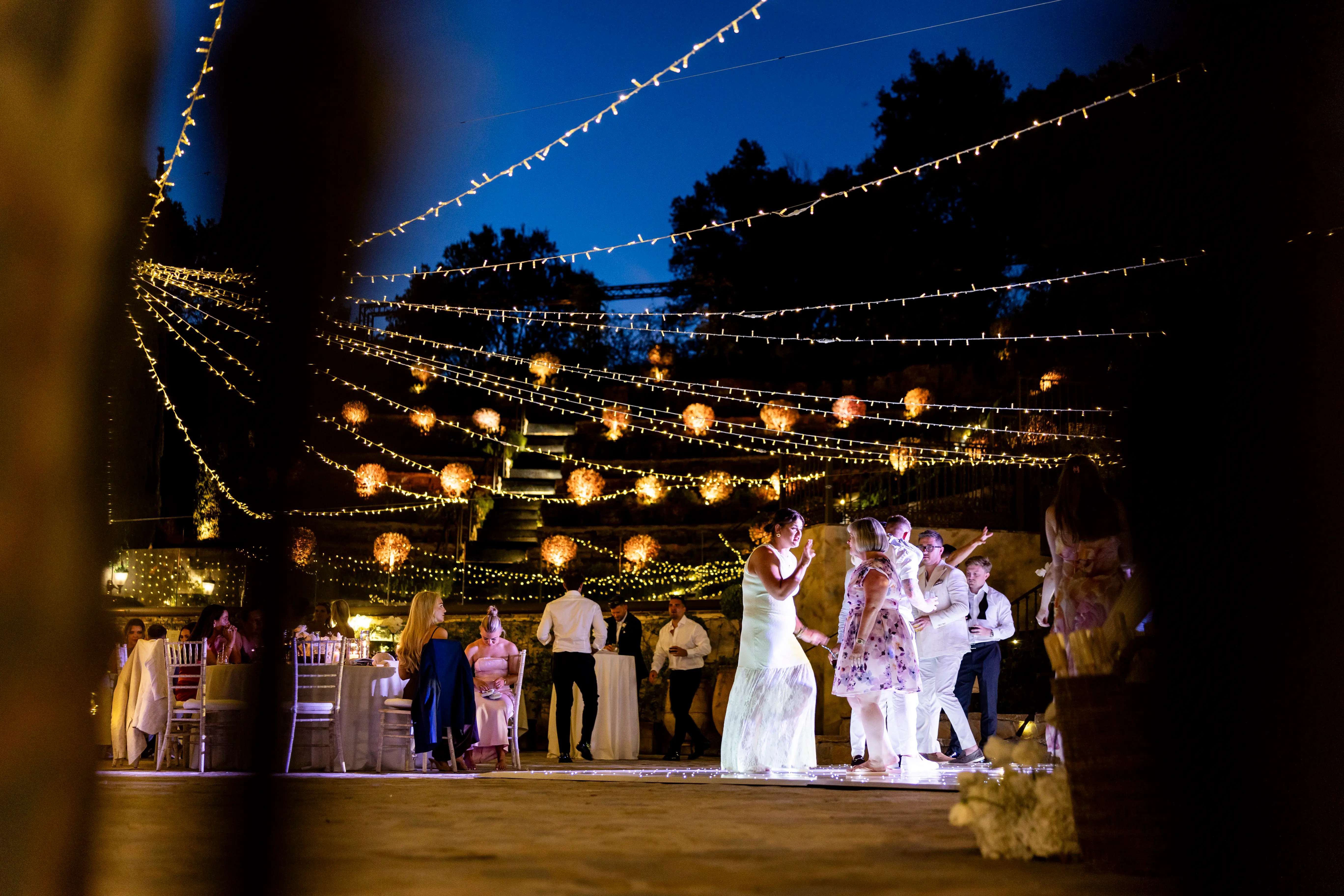 A canopy of festoon and fairy lights over the party at dusk