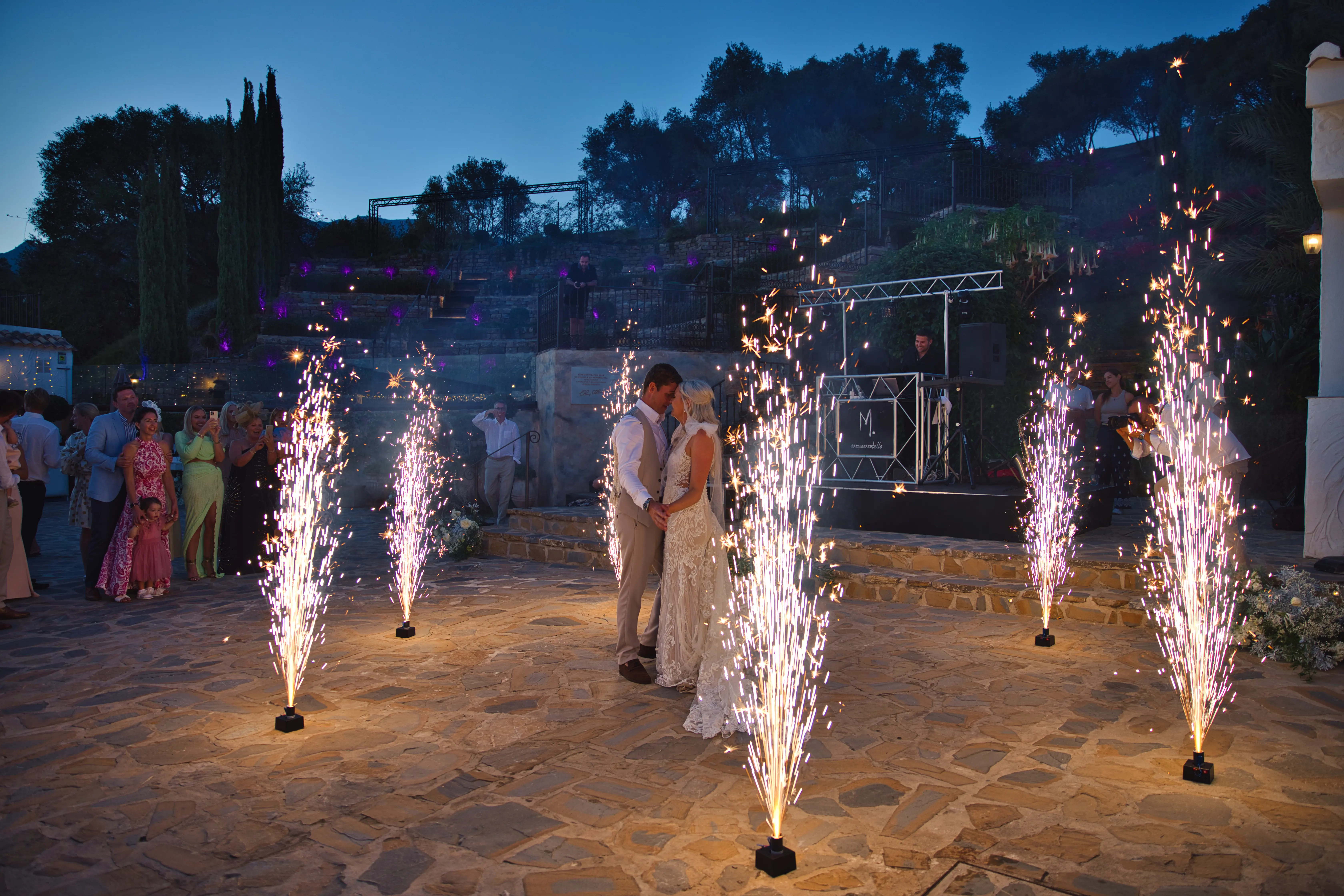A couple's first dance at blue hour, framed by cold spark fountains