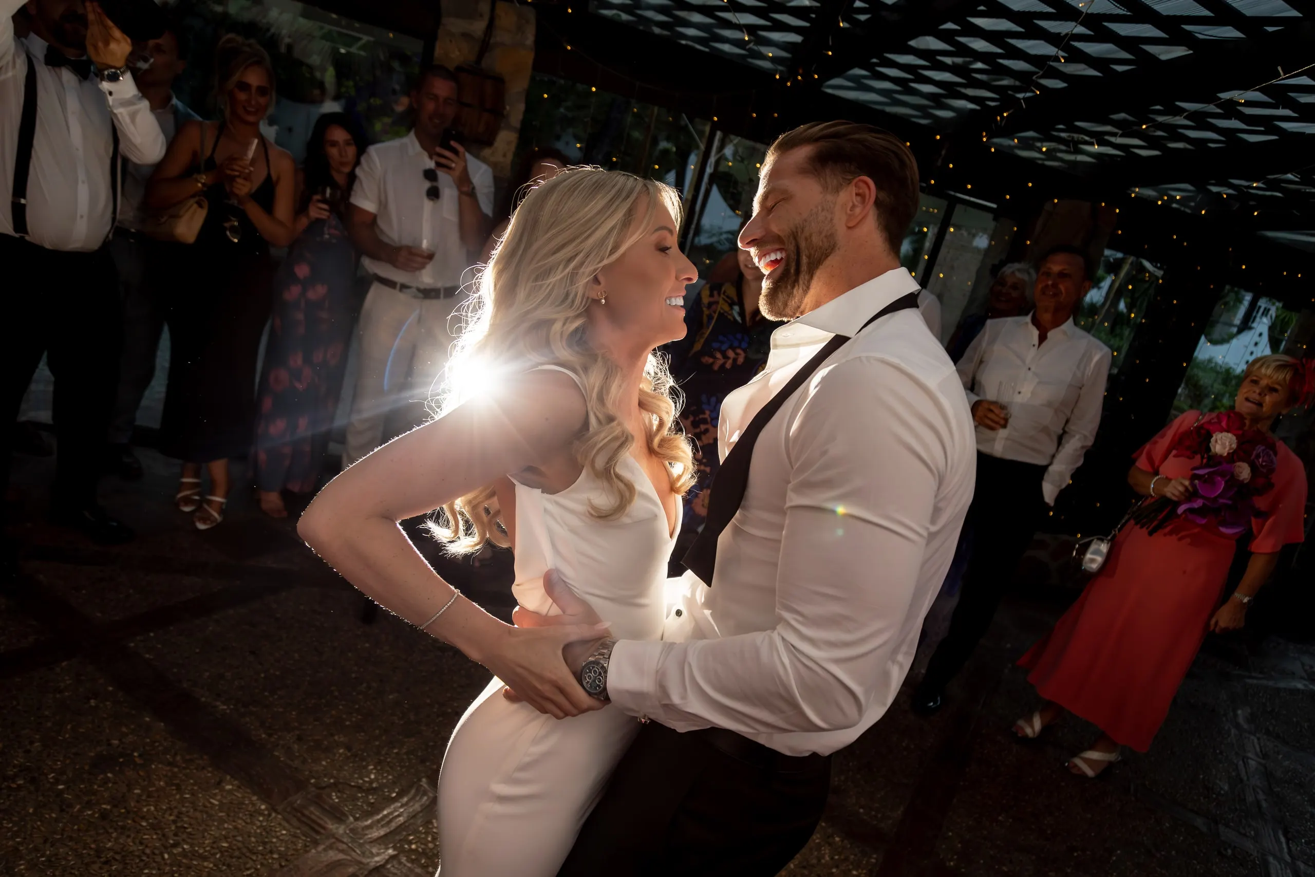 A couple sharing their first dance under warm light as guests watch