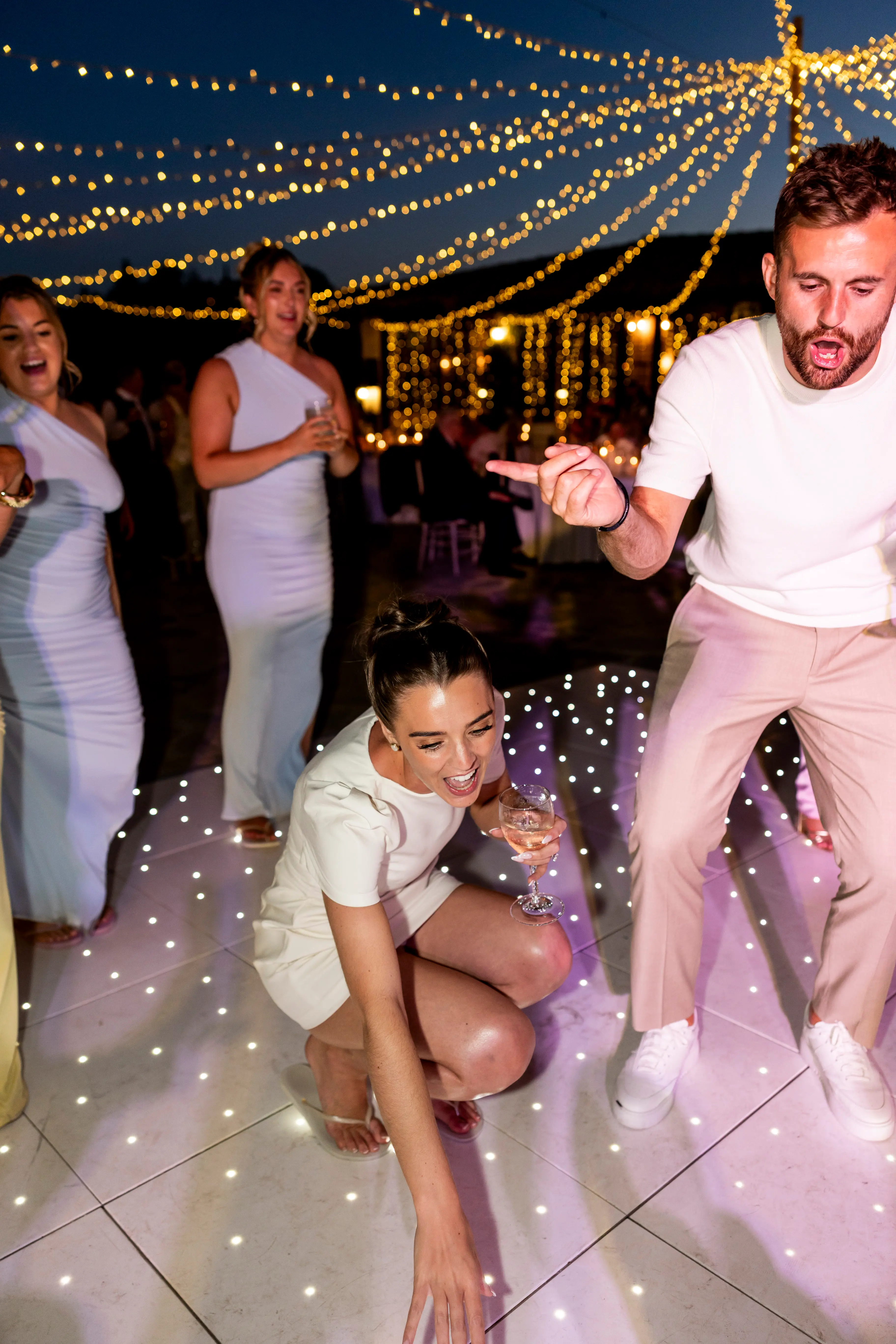 Guests dancing on a starlit LED dancefloor beneath festoon lighting