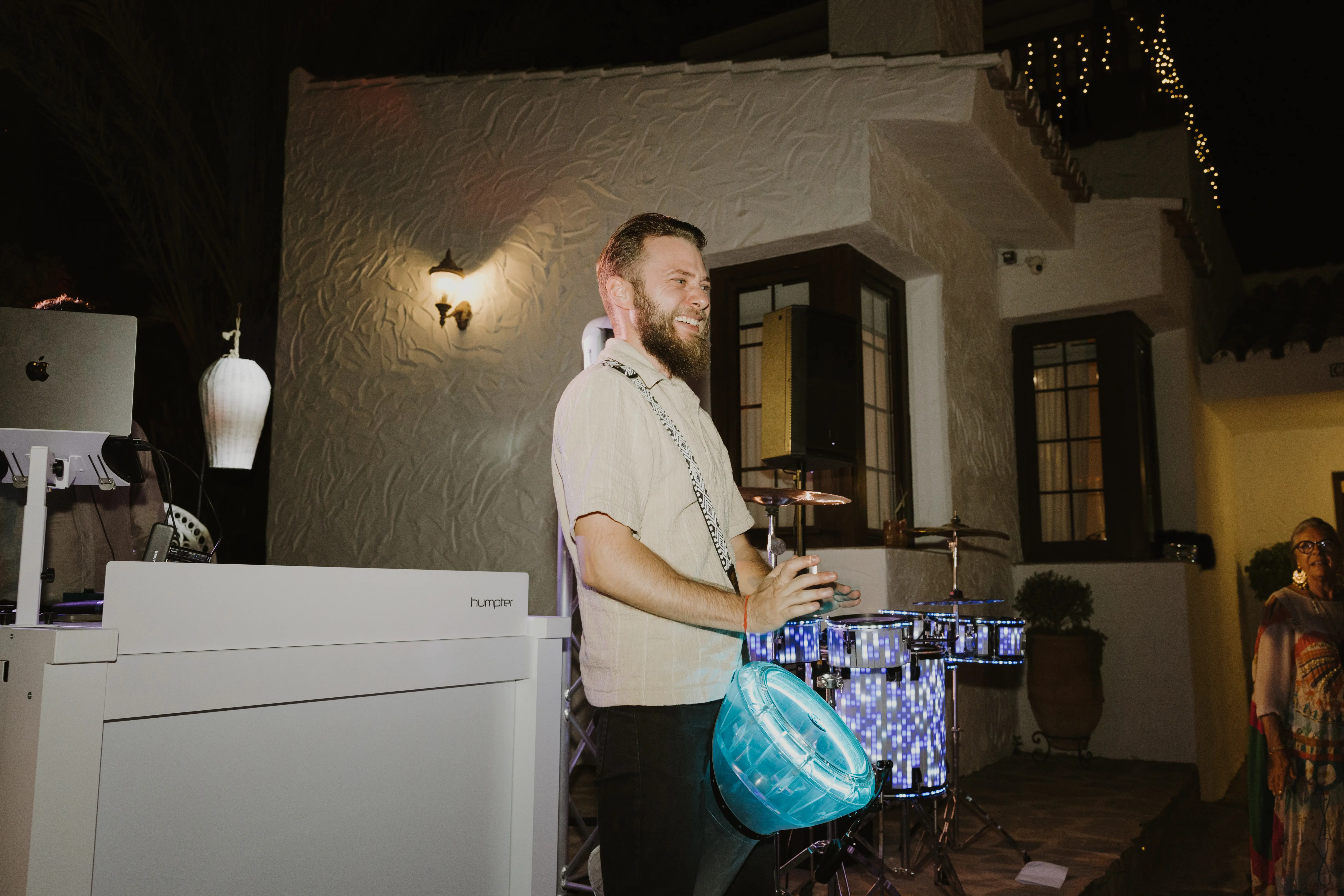 A percussionist playing lit congas alongside the DJ booth