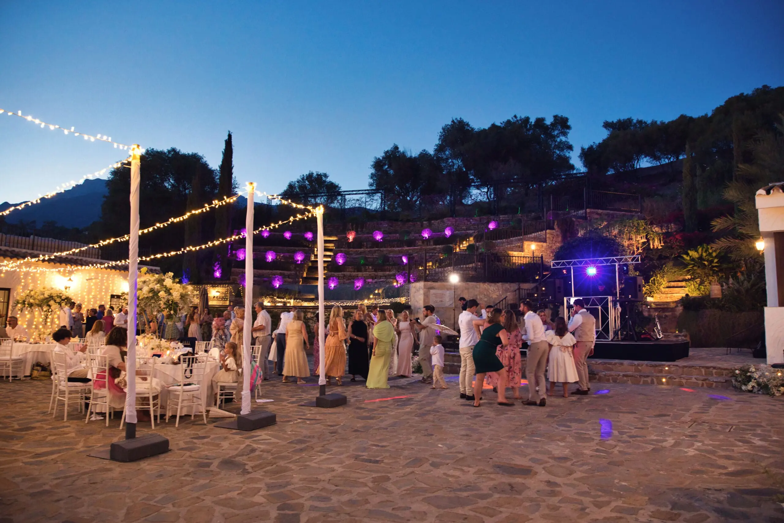 Guests dancing under festoon lights at dusk on a terraced Costa del Sol villa