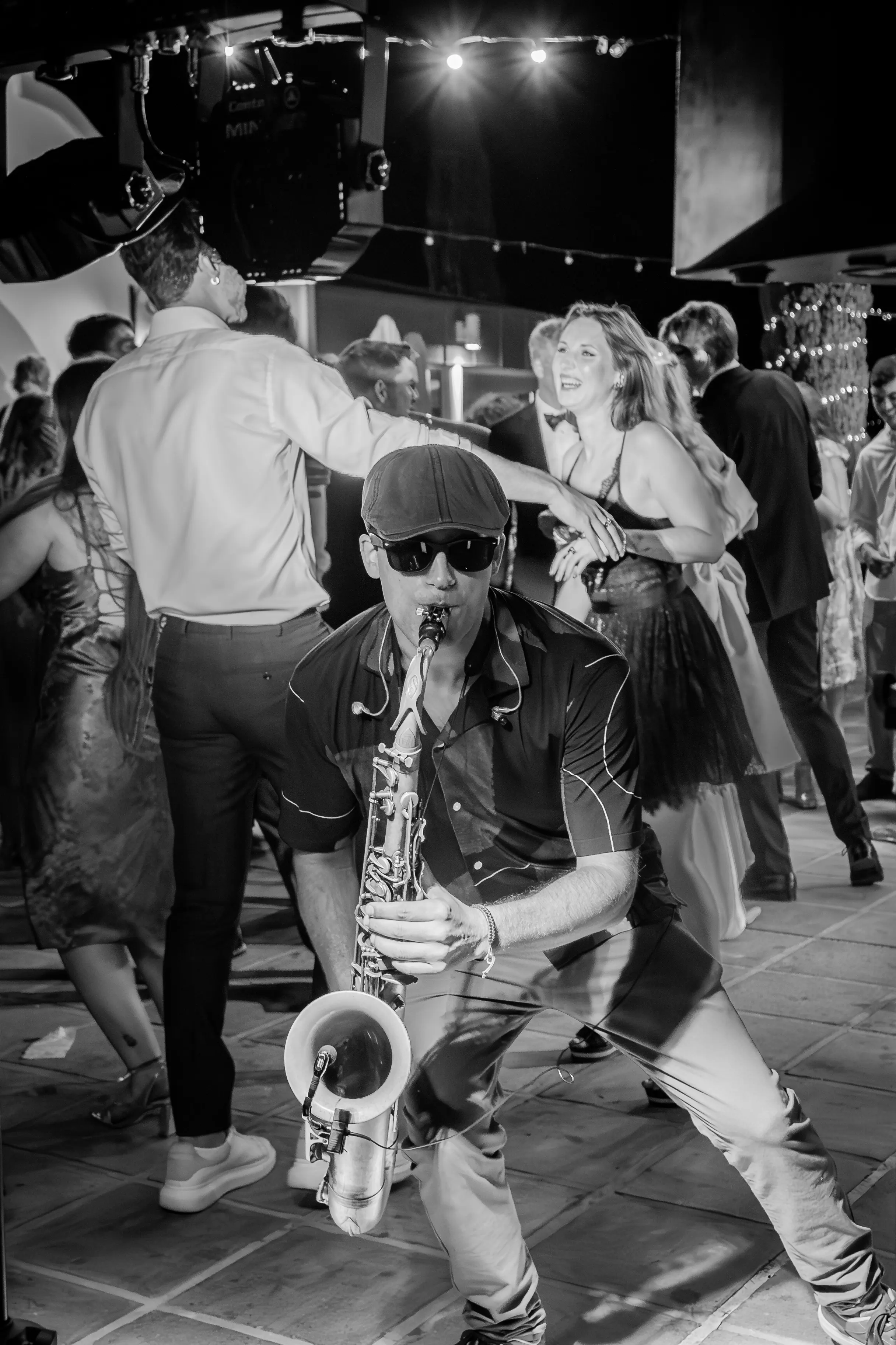 A saxophonist playing among the crowd on a full dancefloor