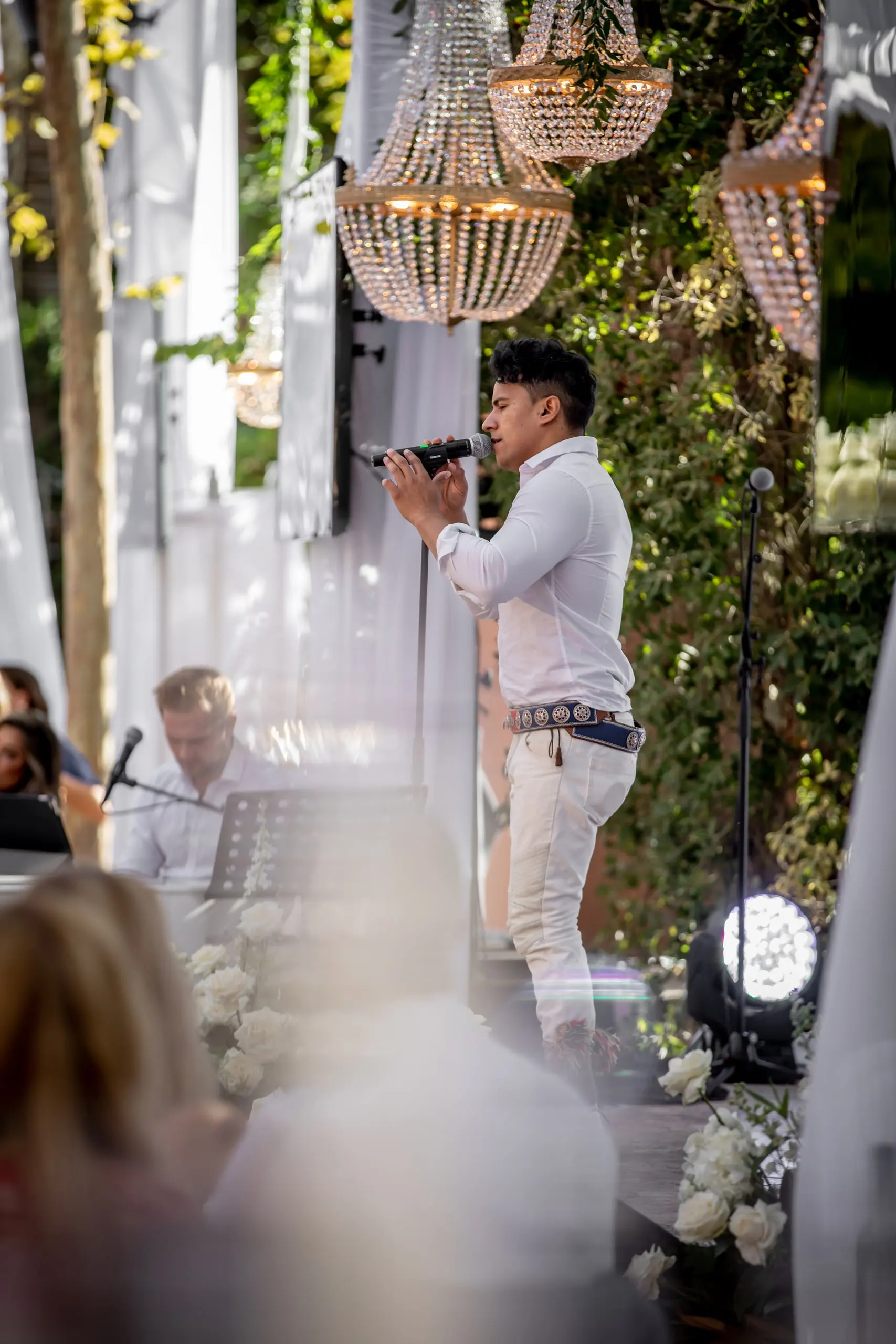 A vocalist performing beneath crystal chandeliers